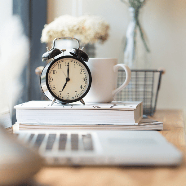 clock, book, and coffee mug sitting on a desk